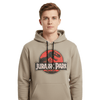 Sweat à capuche unisexe beige avec logo Jurassic Park rouge et noir, porté par un homme. Style casual et confortable pour fans de cinéma.